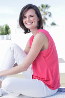 A young woman wearing a pink top and white white trousers