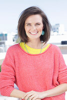 A young woman wearing large earrings, a fuchsia jumper and a yellow top