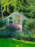 Outdoor living room in greenhouse amongst perennials and shrubs