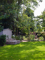 Loungers in shady spot below tall trees in garden