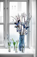 Flowers and branches of pussy willow decorated with paper butterflies on windowsill