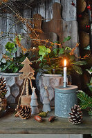 Christrosen mit Zweigen von Zaubernuss, Holzbäumchen, Zapfen und Kerze