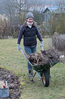 Frau mit Schubkarre voller Gartenabfall