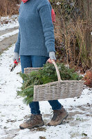 Woman brings basket with freshly cut conifer branches