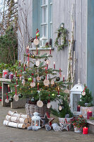 Nordmann fir decorated with wooden discs, Christmas tree balls, fairy lights and candles, stars, lanterns and birch trunks as decoration