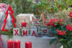 Modern Christmas decoration on the terrace with letters, stars, fir trees, lantern and candles
