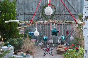 Weihnachts-Mobile als hängende Deko mit Sternen, Zapfen, Kugeln und Woll-Bommeln an Birkenast