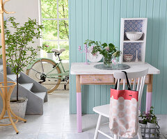 Old desk with legs painted pink against pale blue board wall