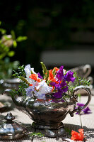 Colourful bouquet of sweet peas and green asparagus in old silver teapot