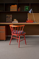 Red spoke-back chair at desk in study in shades of red and orange