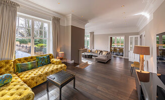 Senfgelbes Übereck-Sofa mit Knopfsteppung auf Splitlevel in elegantem Wohnzimmer
