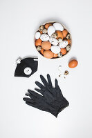 Verschiedene Eier in einer Schüssel, Schutzmaske und schwarze Handschuhe