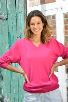 A young woman wearing a pink jumper and white trousers