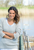 Junge Frau in grauem Pullover am Fluss