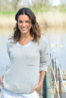 A young woman wearing a grey jumper near river