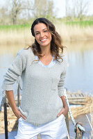 Junge Frau in grauem Pullover und weißen Shorts am Fluss