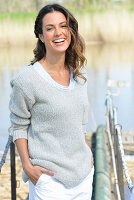 A young woman wearing a grey jumper and white shorts near river