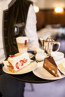 A waiter serving coffee and cake