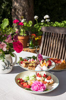 Küchlein, Obst und Blumen auf einer Etagere im sommerlichen Garten