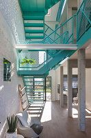 Bright living room with turquoise metal staircase and white brick walls