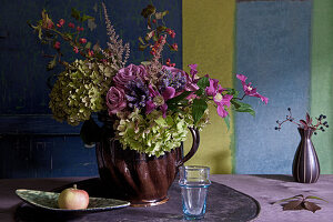 Bouquet of hydrangeas, clematis, roses, astilbes and spindle fruits in farmhouse jug