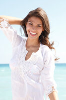 Dark-haired woman in a white blouse laughing by the sea