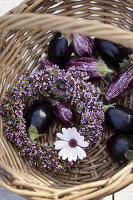 Kranz aus blühendem Thymian im Korb mit Auberginen und Blüte