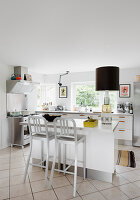 Bar stools at island counter in white, modern kitchen