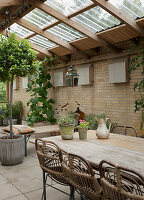 Rattan chairs at dining table in conservatory with brick walls