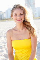 Blonde Frau in gelbem Bandeau-Kleid am Strand