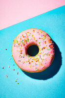 Ein Erdbeer-Donut mit rosa Zuckerglasur und Zuckerstreuseln