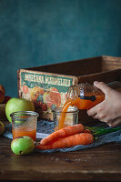 Möhre-Apfel-Saft in ein Glas gießen