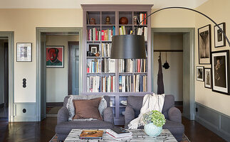 Grey armchairs, coffee table and arc lamp in front of bookcase