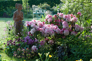 Frühsommerbeet mit Rhododendron 'Silberwolke', Zierlauch, Hornveilchen, Akelei und Funkie, Frauenfigur aus Terracotta