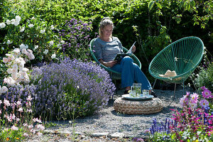 Frau entspannt sich im Garten neben Lavendel und Rosen