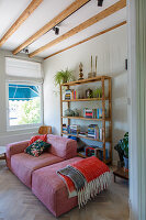 Pink sofa set in front of shelves in living room with herringbone parquet floor