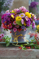 Herbststrauß aus Astern, Chrysanthemen, Sommerastern, Hagebutten und Zieräpfeln, Vase verkleidet mit Filz