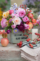 Autumn bouquet made of roses, asters and rose hips in a wooden box