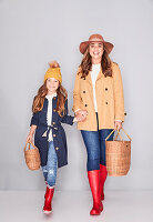 Mutter und Tochter im Partnerlook (Kopfbedeckung, Jacke, Jeans und rote Gummistiefel)