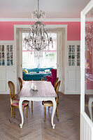 Dining table and antique chairs below chandelier