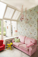Pink sofa against wallpaper with bird motif in girl's bedroom