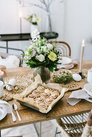 Hefeschnecken auf gedecktem Ostertisch mit Blumenstrauß