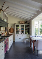 A classic eat-in kitchen in shades of grey with a conservatory and a beamed ceiling