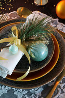 Pine twig and turquoise Christmas-tree bauble on napkin
