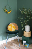 Yellow velvet cushion on retro chair against dark green wall