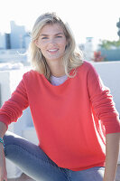 A young blonde woman wearing a coral-coloured turtle-neck jumper