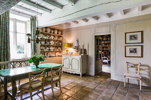 Table with top in green glazed ceramic, crockery shelves and chest of drawers in the dining room