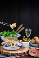 Classic baked french Mont d'or vacherin cheese with cornichons, boiled potatoes and sliced ham
