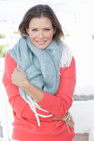 A young woman wearing a thick scarf and a coral jumper