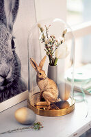 Gold-coloured Easter bunny and posy of flowers under glass cover